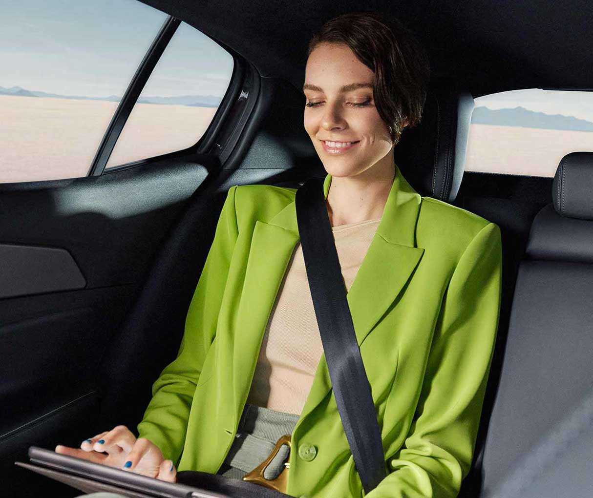 Жінка користуєть планшетом, сидячи на задньому сидінні автомобіля Peugeot